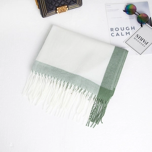 Detailed flat lay of soft beige and sage green cashmere-like scarf with fringe details