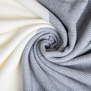 Close-up of high-quality cashmere-like gray and beige patchwork woven scarf texture