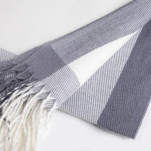 Macro shot of grey and white checkered cashmere-feel scarf with elegant fringe detail