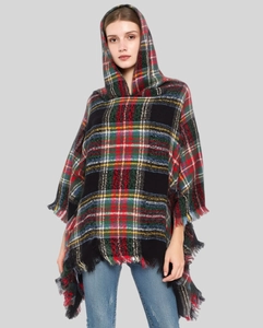 Detail of red and green plaid hooded poncho featuring soft wool blend and fringe tassels