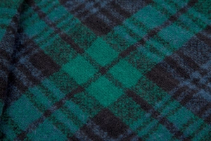 Close-up of green and black plaid knit fabric showing the detailed thick winter texture