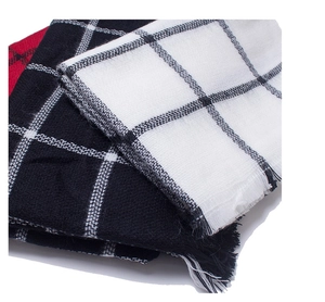 Detail of soft cashmere-like scarves showing woven plaid texture and tassel edges