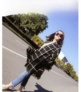 Detailed view of black and white plaid scarf with fringe on a model in outdoor setting