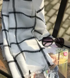 Detail view of black and white plaid scarf with fringe edges on a wooden bench
