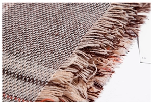 Close-up of thick brown plaid scarf fabric showing soft texture and fringe tassel detail