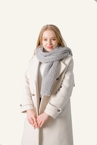 Close-up of grey chunky knit scarf with vertical texture on white wool coat