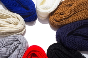 Macro detail of multi-colored rib-knit scarves showing rich texture and variety