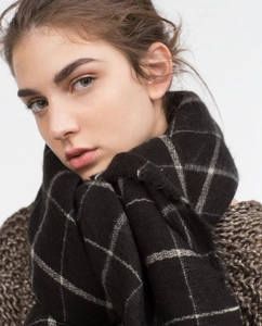 Detail of soft black and white plaid scarf texture worn over a brown knit sweater