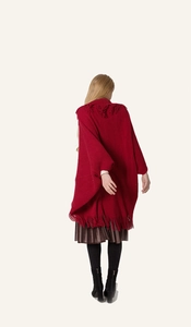 Gros plan du poncho en maille rouge avec détails de franges sur l'ourlet et l'épaule