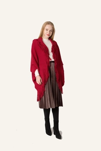 Détail d'un cardigan cape en maille rouge avec franges denses et style bohème