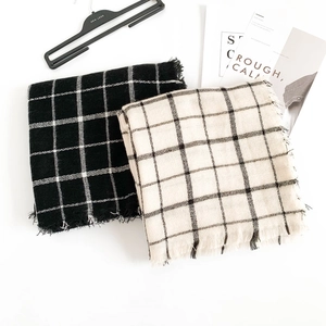 Macro shot of minimalist plaid scarves with fringe details in black and cream
