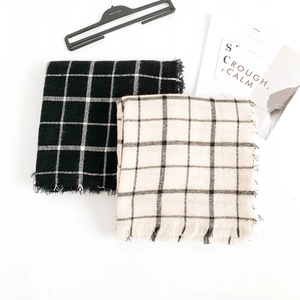 Flat lay of black and white plaid scarves with tassels and fashion magazine backdrop