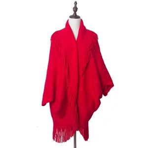 Détail des longues franges sur un cardigan en tricot rouge vif de style bohème