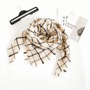 Detail shot of soft cashmere-like shawl with black windowpane grid and tassel edges