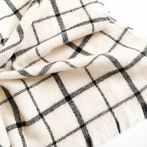 Close-up of black and white plaid scarf fabric with soft cashmere-like texture and tassels