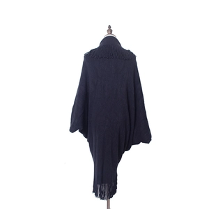 Détail d'un châle poncho en maille noire avec de longues franges et une silhouette drapée