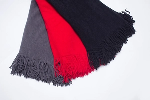 Gros plan de gilets en tricot gris, rouges et noirs avec de longues franges