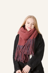 Detail of thick brick red scarf with long tassels paired with a black wool coat