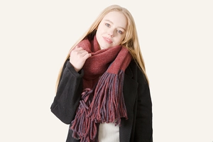 Detailed view of the thick burgundy knit scarf with bicolor long fringe accents