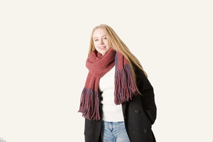 Close-up of thick terracotta winter scarf with heavy tassels and soft knit texture