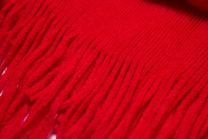 Gros plan sur la maille côtelée rouge et les franges douces d'un châle d'hiver chaud