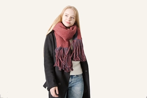 Detail of burgundy thick knit scarf with long tassels and contrast color styling