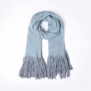 Detailed view of light blue knitted scarf texture with dense matching tassels at the ends