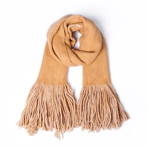 Detailed close-up of thick ginger yellow knit scarf with long fringe and soft texture