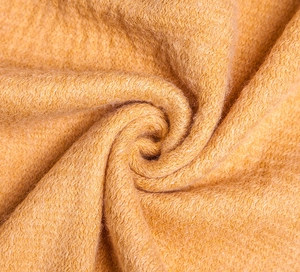 Macro view of thick ginger yellow wool-like fabric with soft rich texture and tassels