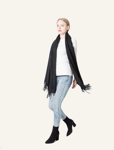 Detail of soft black cashmere-feel scarf with fringe ends worn with casual outfit