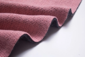Macro detail of thick double-sided knit fabric in dusty pink and black for warm winter scarves