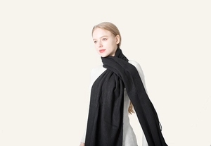 Detail of soft black faux cashmere scarf with fringe edges worn over a white turtleneck