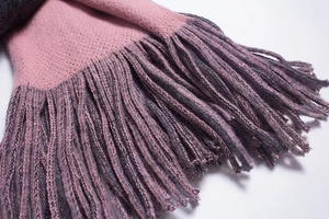 Close-up of pink and dark grey knitted scarf featuring fine fringe and soft texture