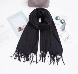 Detailed flat lay of black cashmere-like scarf with twisted tassels and fashion accessories
