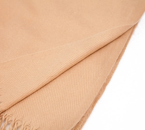 Detailed close-up of camel cashmere-feel scarf texture with fringe tassel edge