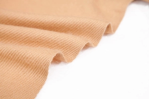 Detailed close-up of soft camel cashmere pashmina shawl with fine twill texture and drapes