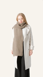 Detail of chunky knit brown scarf showing thick texture paired with a white coat