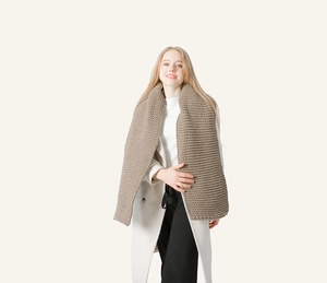 Detail view of thick dark camel chunky knit scarf with premium woolen texture on model