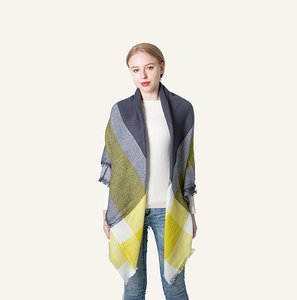Detail of grey and yellow plaid scarf showing fine texture and fringed edges on a model