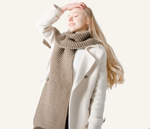 Close-up of chunky knit camel scarf with honeycomb texture on a white coat