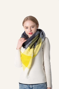 Detail of warm yellow and grey plaid winter shawl scarf over a white knit sweater
