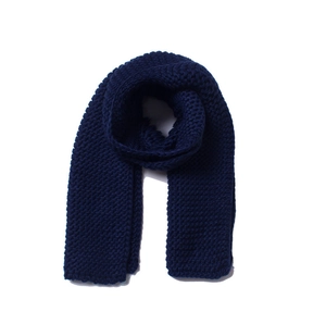 Detailed close-up of dark blue chunky knit scarf showing wave-like texture on white background