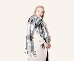 Close-up of thick plaid scarf featuring black, white, and grey checks with fringe detail