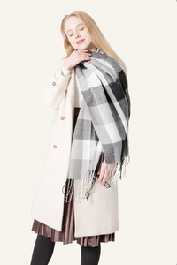 Detailed view of the soft black and white plaid scarf featuring elegant tassel fringe edges