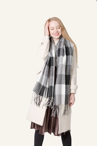 Detail of grey and black plaid scarf with long fringe tassels on a soft beige coat