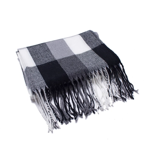 Close-up of black and white plaid scarf featuring thick tassels and soft woven texture