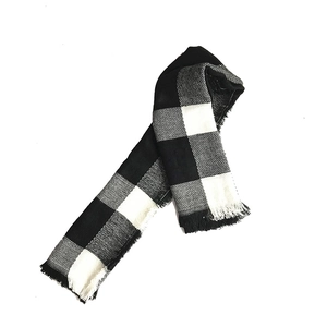 Close-up of classic black and white plaid scarf featuring soft fringe and thick texture