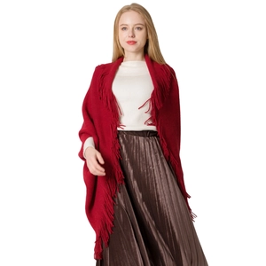Cardigan en maille rouge foncé avec de longues franges porté sur une jupe plissée