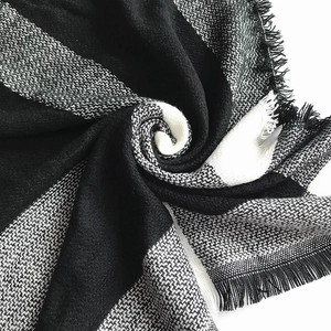 Detail of black and white cashmere-like scarf showing soft knitted texture and tassels