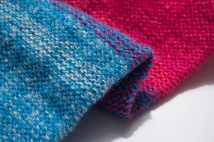 Detailed macro shot of thick knit winter scarf showing blue and pink wool texture